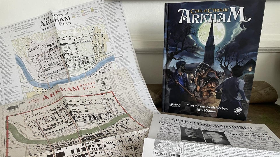 An image of Call of Cthulhu: Arkham and its various included player resources, like a map and fake newspaper.