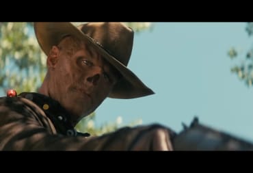 A ghoul looking down and to the right, pointing a gun at something.