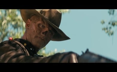 A ghoul looking down and to the right, pointing a gun at something.