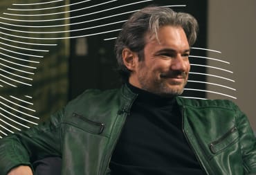 Returnal director Harry Krueger looking relaxed in a green jacket and black shirt