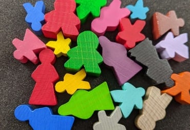 A screenshot of multiple meeples of different sizes, shapes, and colors on a black background.