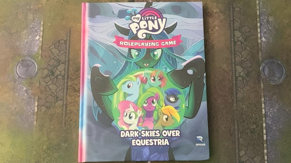 A photo of a copy of My Little Pony: Dark Skies Over Equestria on a gaming mat.