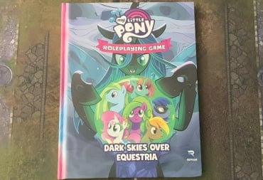 A photo of a copy of My Little Pony: Dark Skies Over Equestria on a gaming mat.