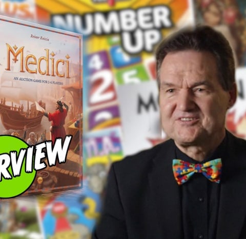 Reiner Knizia and the Medici box against a background of his other games